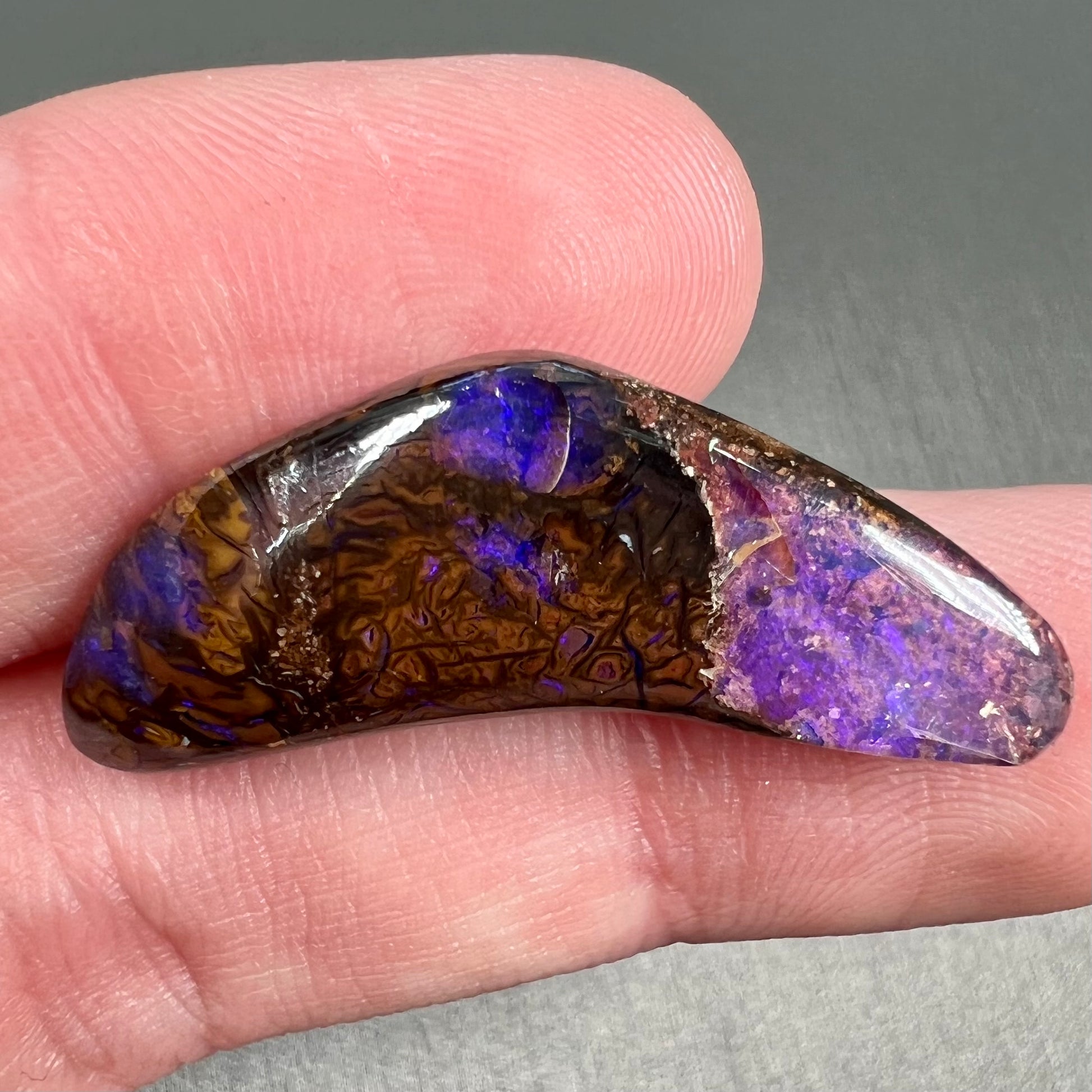 A loose boomerang shaped purple boulder opal stone from Quilpie, Australia.