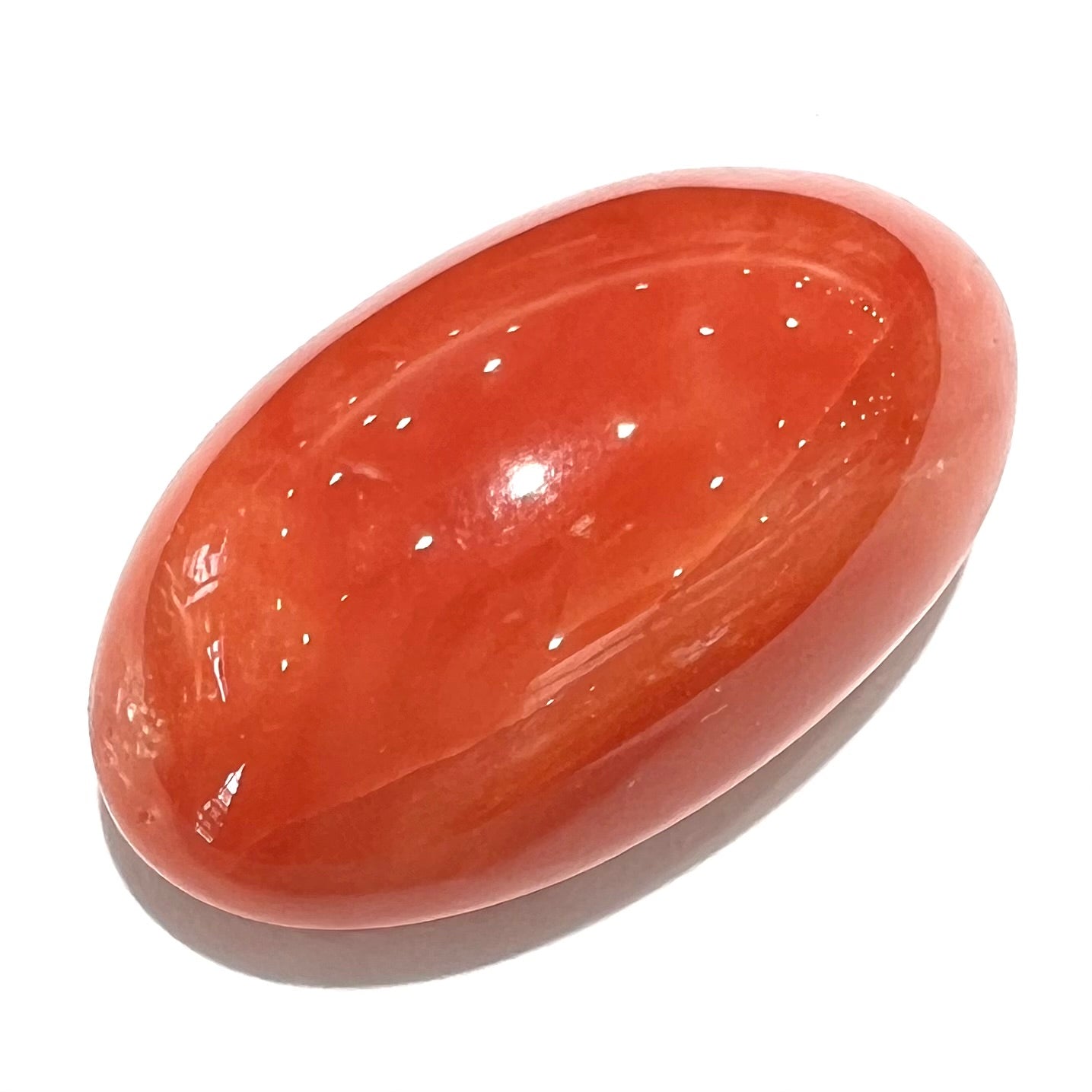 A large, loose red-orange coral cabochon that measures 1.2 inches by 0.7 inches.
