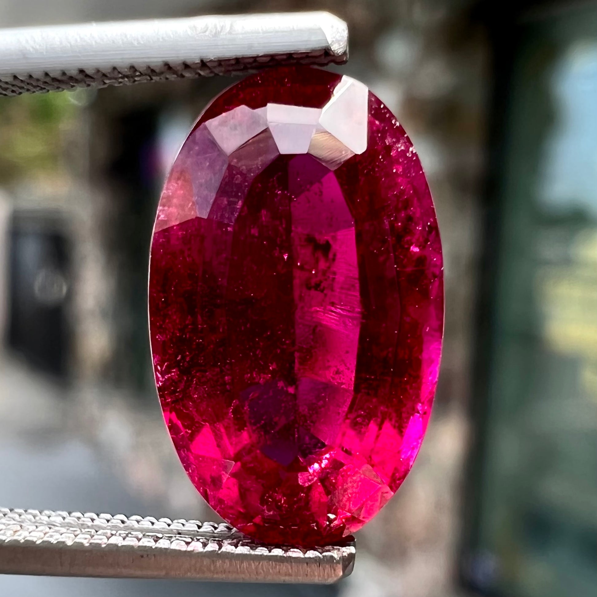 A loose, oval cut, purplish red rubellite tourmaline stone.