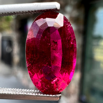 A loose, oval cut, purplish red rubellite tourmaline stone.