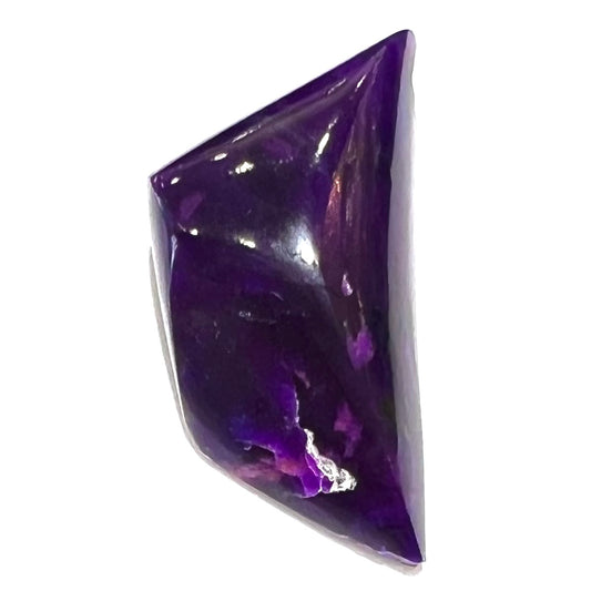 A freeform cabochon cut piece of dark purple sugilite.