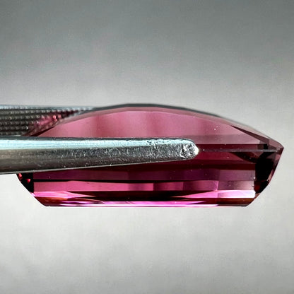 A loose, fantasy cut reddish colored tourmaline.  The cut reflects light in a way that resembles digital pixels on a screen.