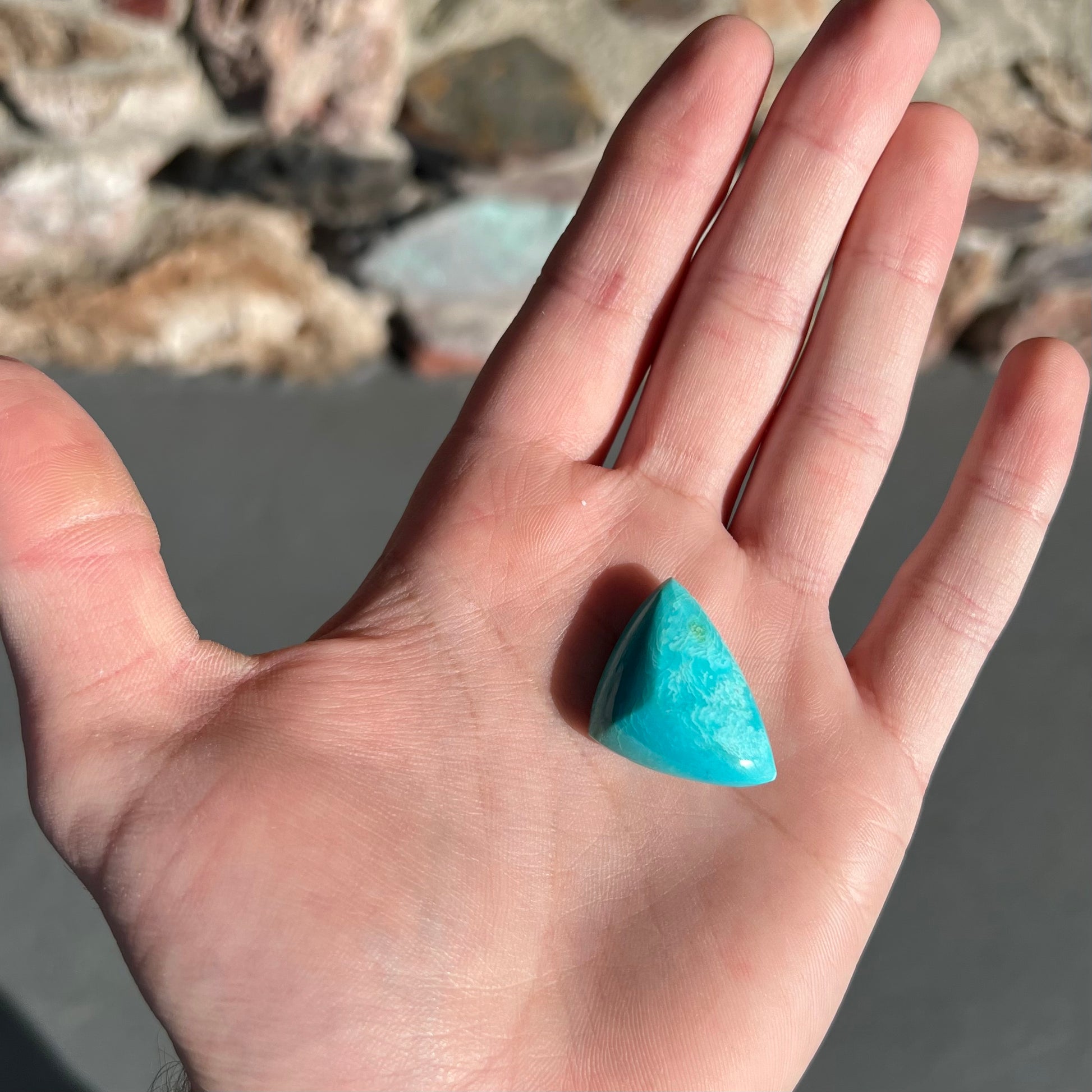 A loose triangular cabochon cut blue turquoise stone from the Sleeping Beauty Mine in Arizona.