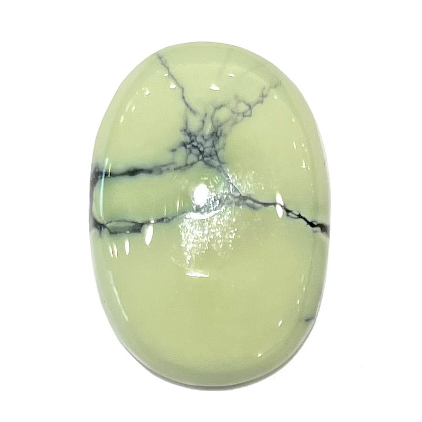 A loose, oval cabochon cut variscite stone from Utah, USA.  The stone is yellow-green with a black matrix.