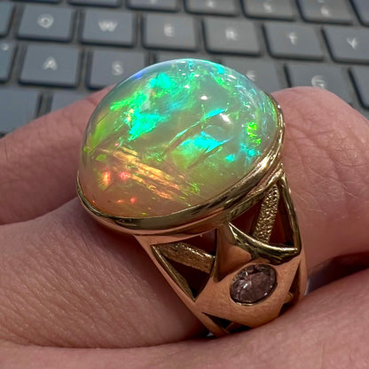 A custom yellow gold men's ring set with two diamonds and a large oval cabochon cut opal from Ethiopia, Africa.