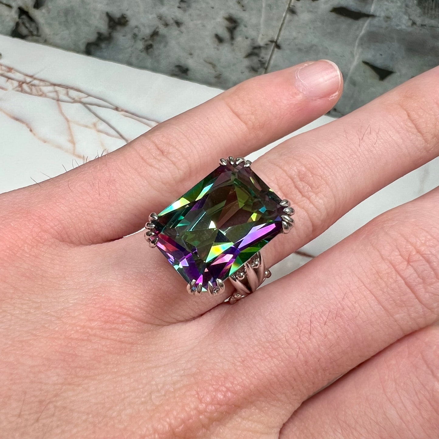 Emerald cut mystic topaz prong set in a decorative sterling silver ring.
