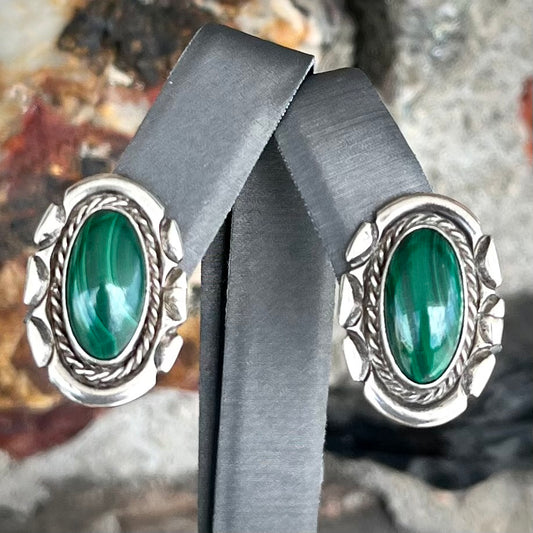 A pair of Southwest style post earrings set with oval cabochon cut malachite stones.