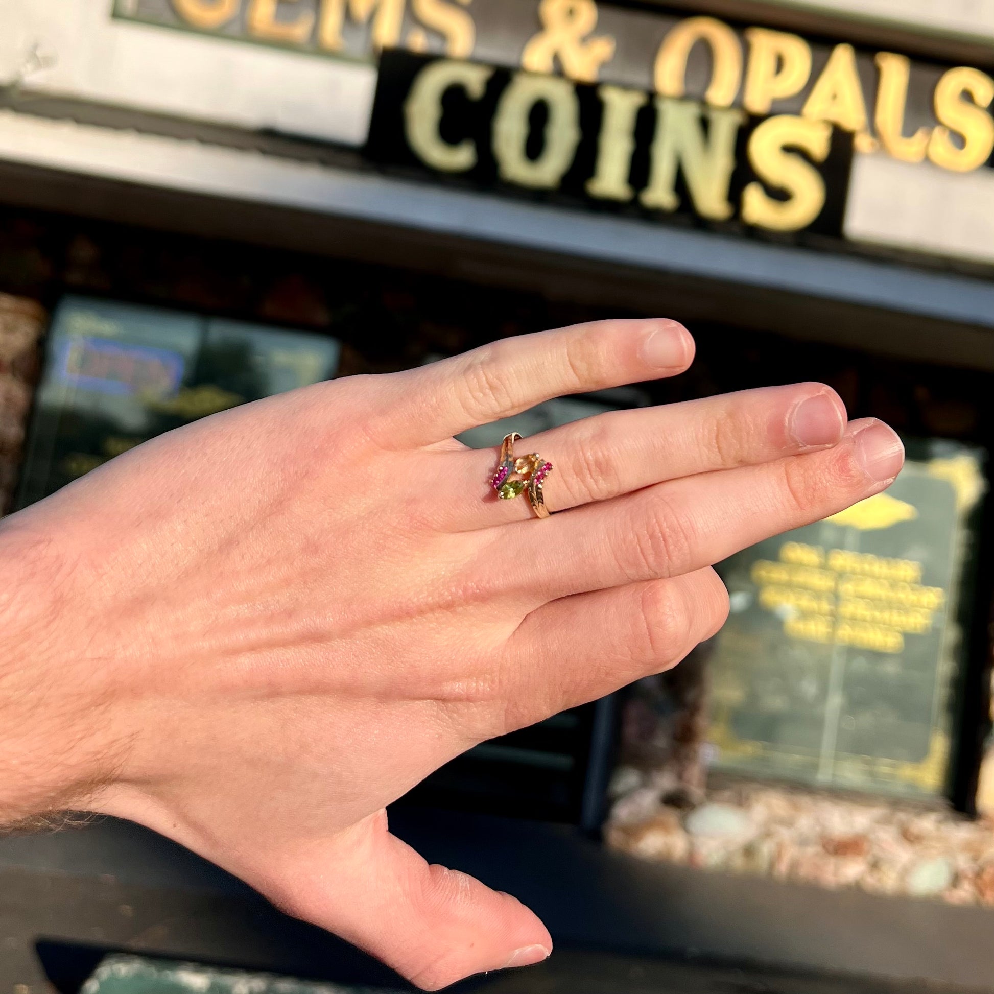 A gold twisted shank ring set with a marquise cut citrine, marquise cut peridot, and round cut ruby accents.