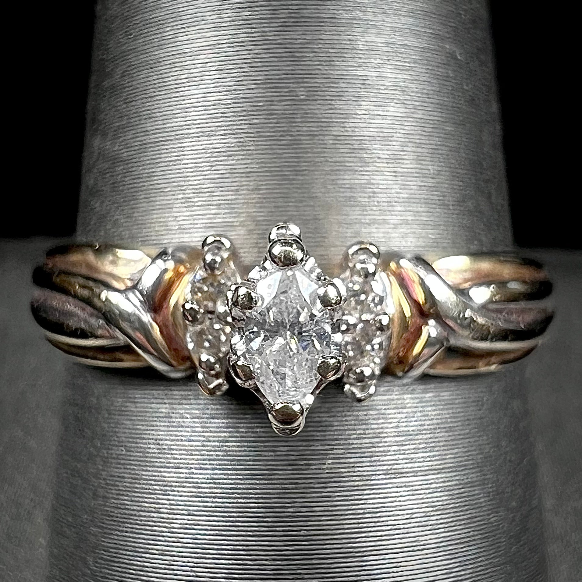 A ladies' two-tone white and yellow gold marquise cut diamond enagagement ring.  There are round diamond accents.