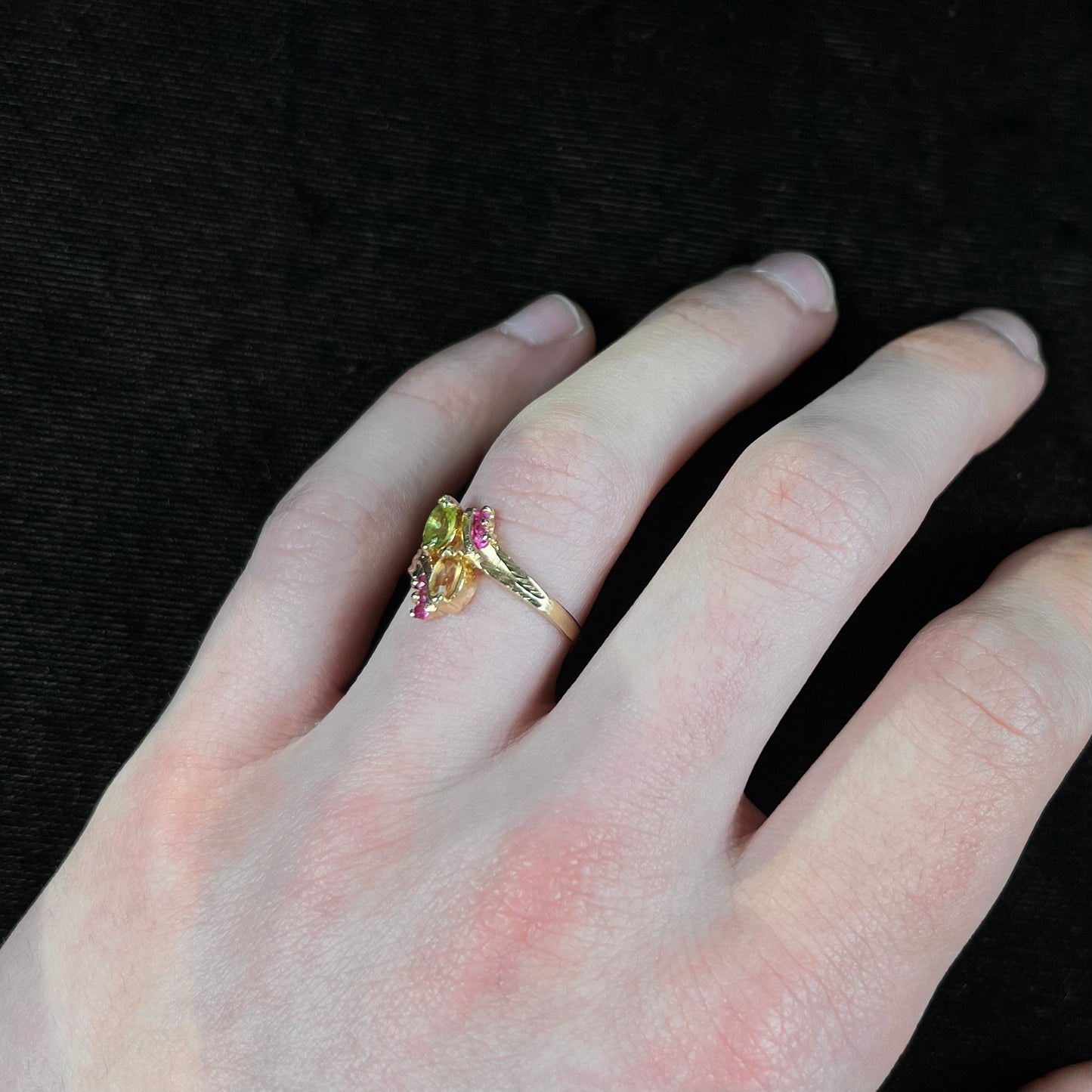 A gold twisted shank ring set with a marquise cut citrine, marquise cut peridot, and round cut ruby accents.