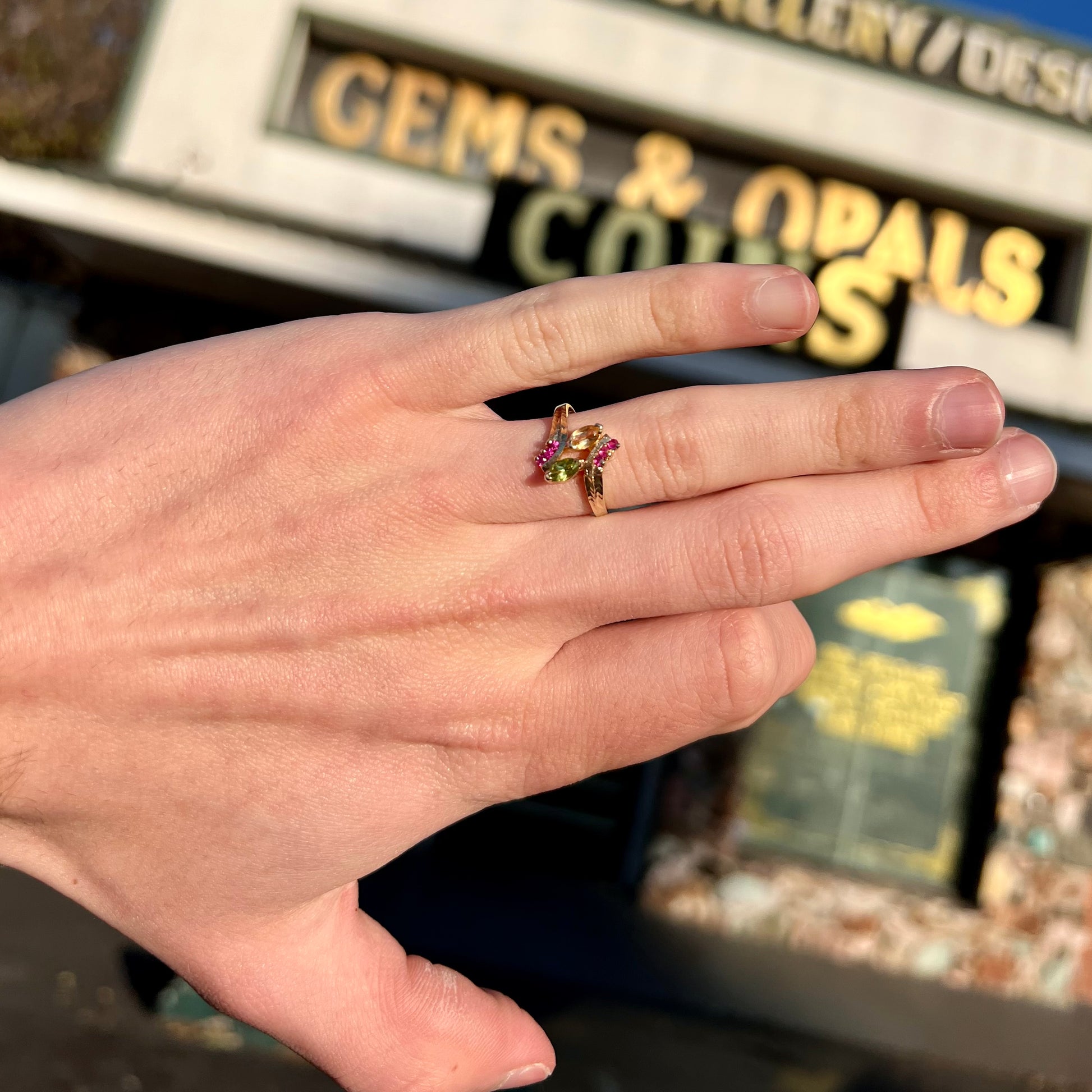 A gold twisted shank ring set with a marquise cut citrine, marquise cut peridot, and round cut ruby accents.