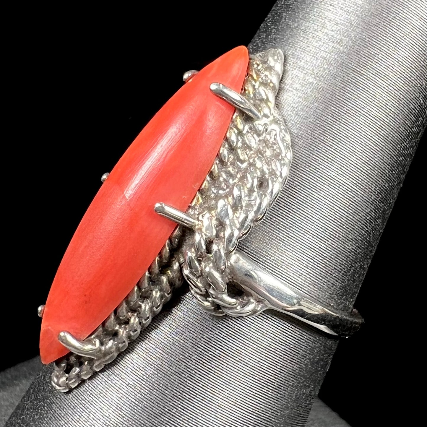 A prong-set silver ring set with a red marquise cut coral.