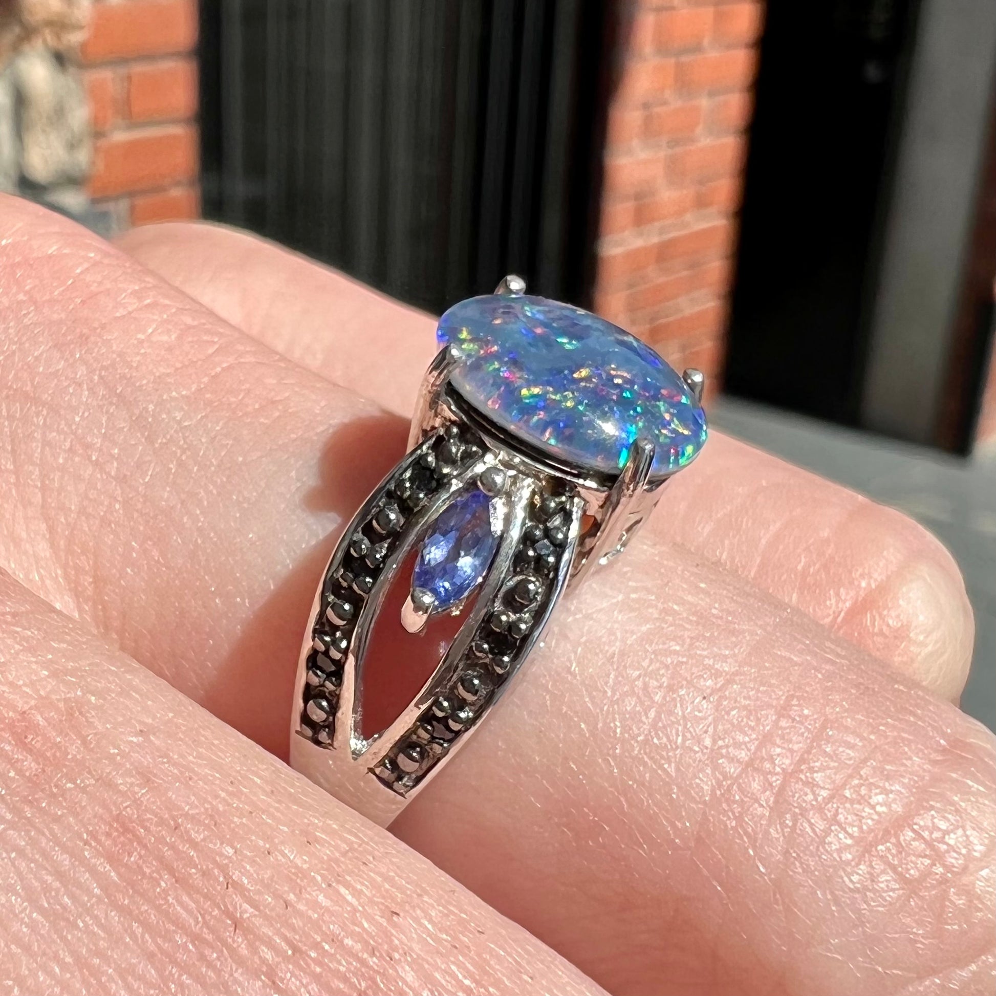A sterling silver black opal triplet ring set with black spinel and marquise cut tanzanite accent stones.