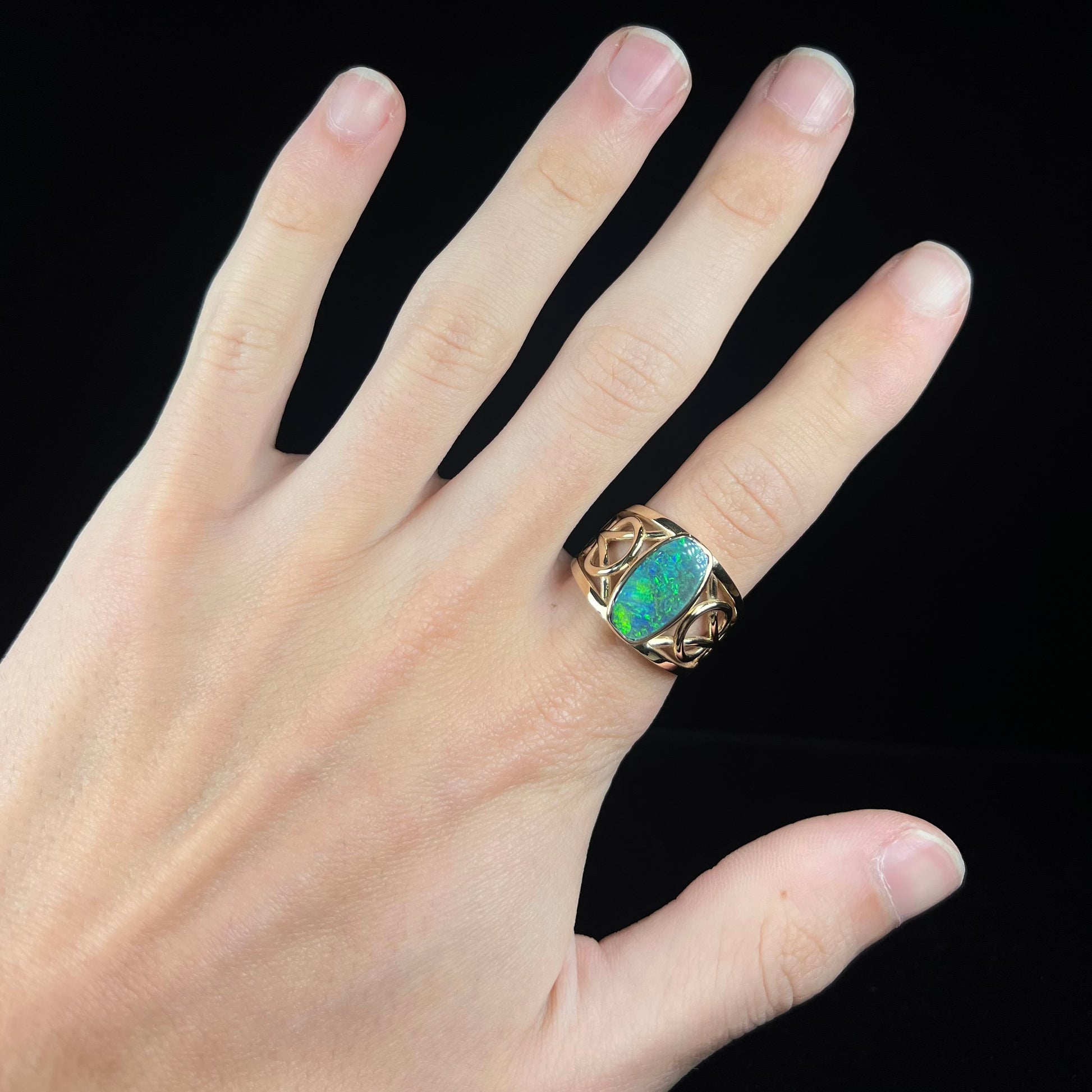 A men's natural Lightning Ridge, Australian black opal solitaire ring cast in yellow gold.