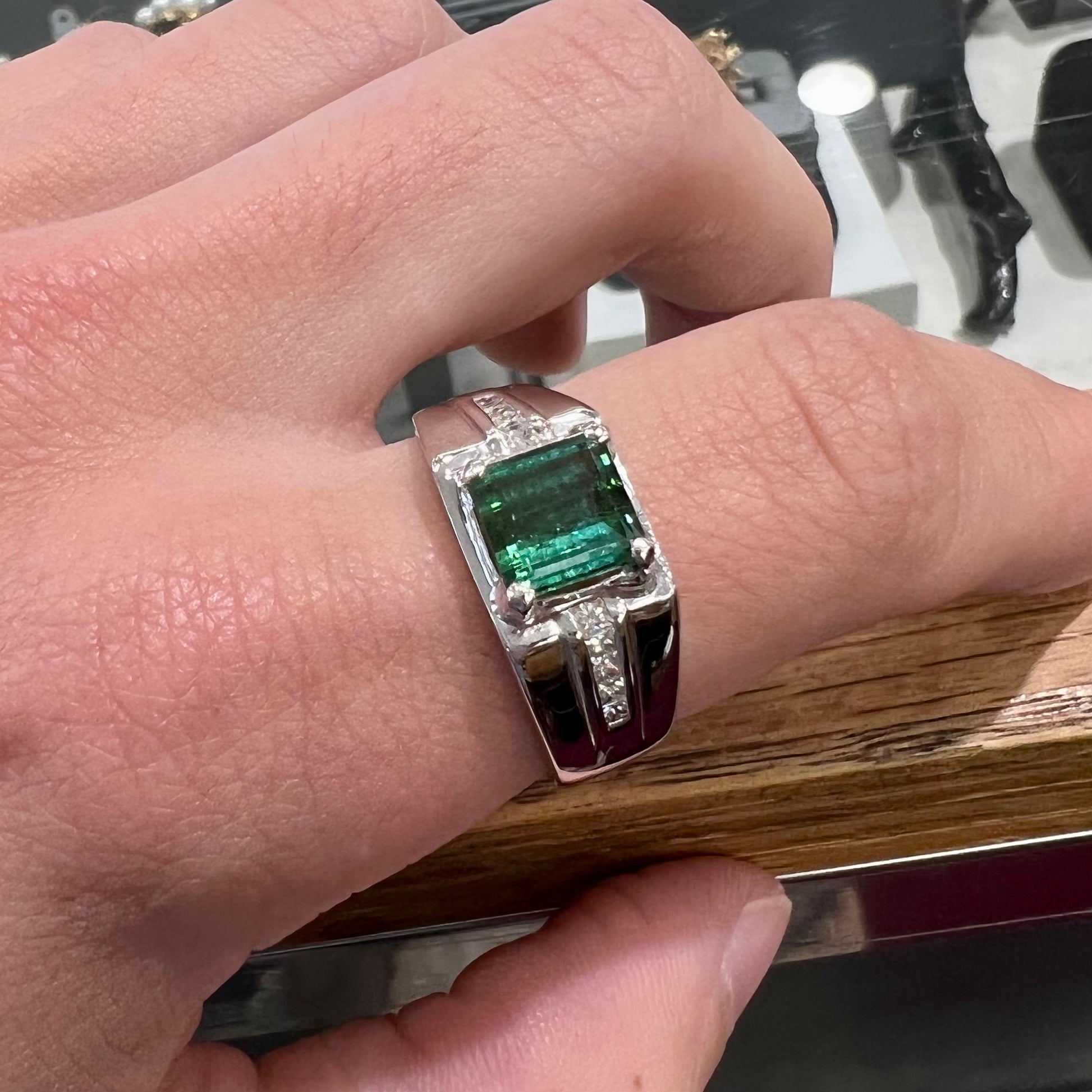 An 18k white gold green tourmaline and diamond men's ring.  The stones are princess cut.