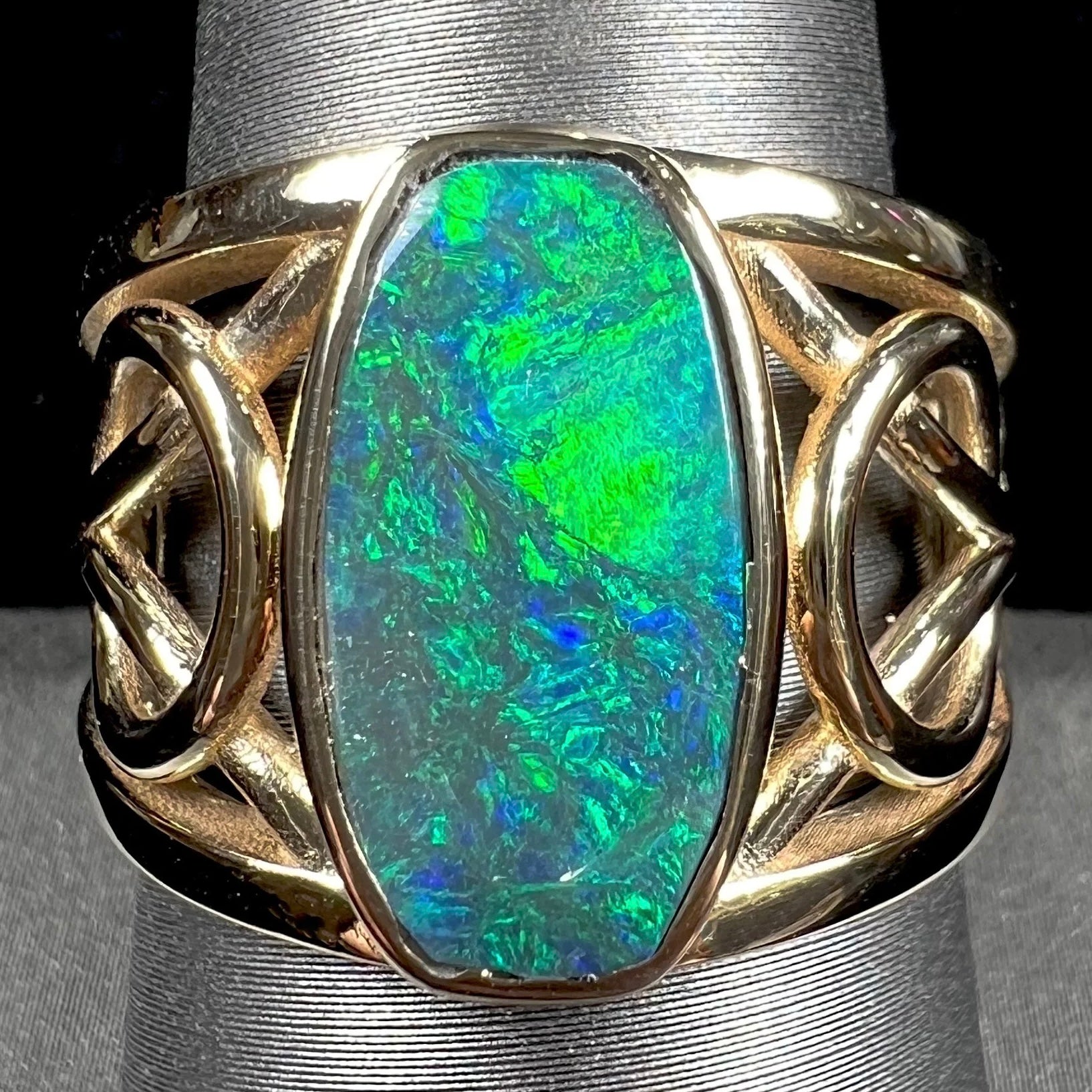 A men's natural Lightning Ridge, Australian black opal solitaire ring cast in yellow gold.