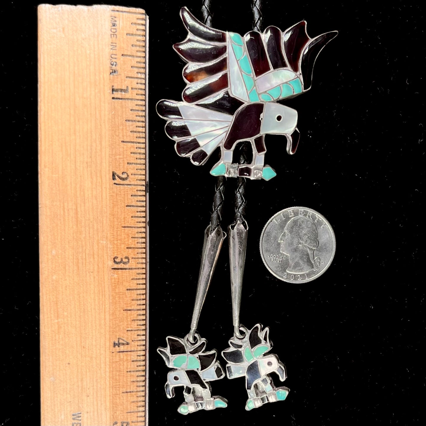 A sterling silver Zuni Indian-made bolo tie featuring the motif of three flying eagles inlaid with natural stones.