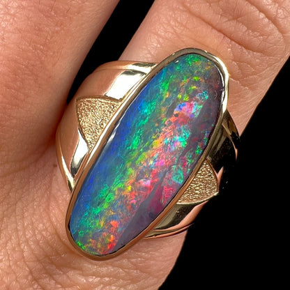 A men's two-tone gold solitaire ring set with a natural boulder opal from Koroit Mining District, Australia.