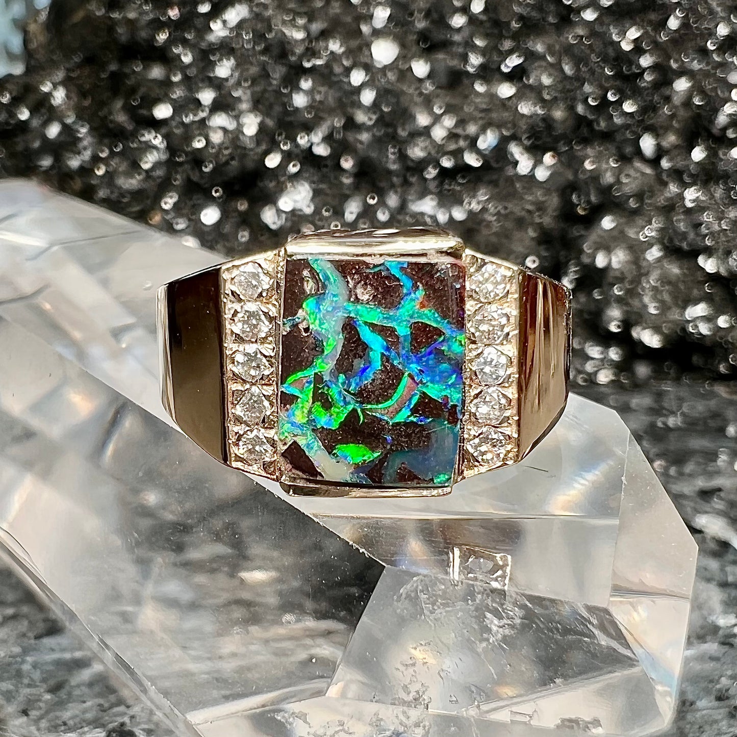 A men's gold boulder opal and diamond ring.  The opal shows blue and green colors.