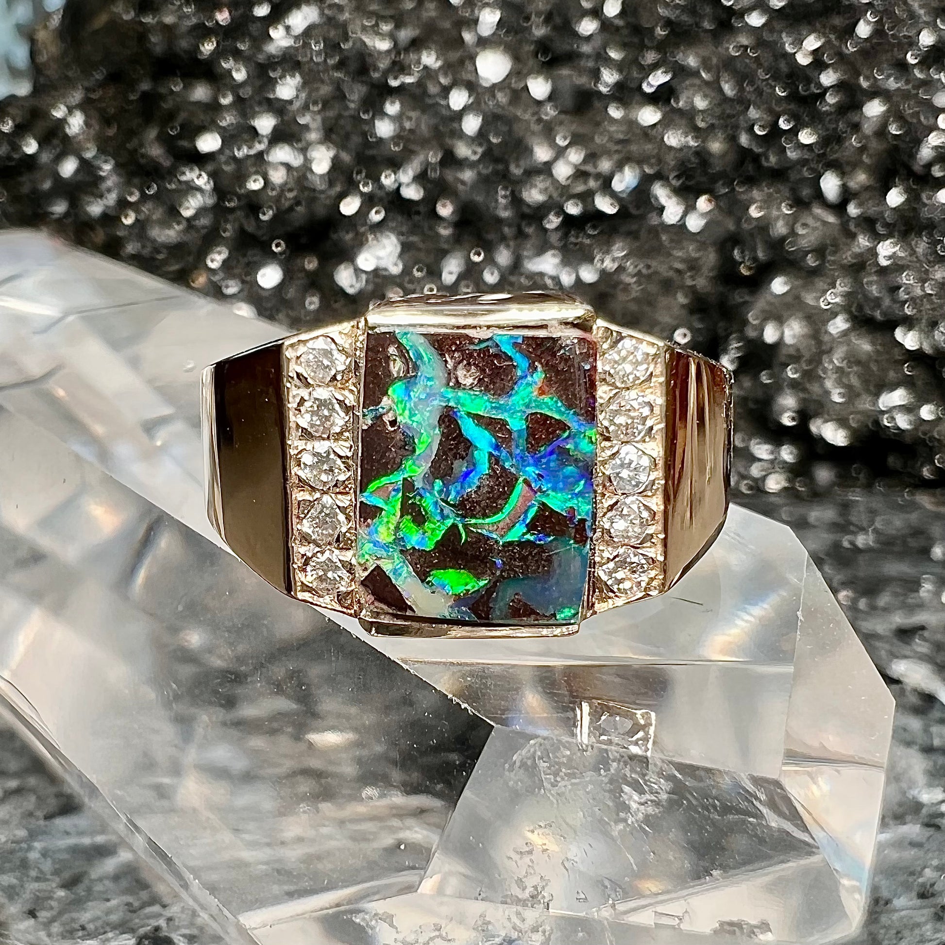 A men's gold boulder opal and diamond ring.  The opal shows blue and green colors.