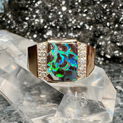 A men's gold boulder opal and diamond ring.  The opal shows blue and green colors.