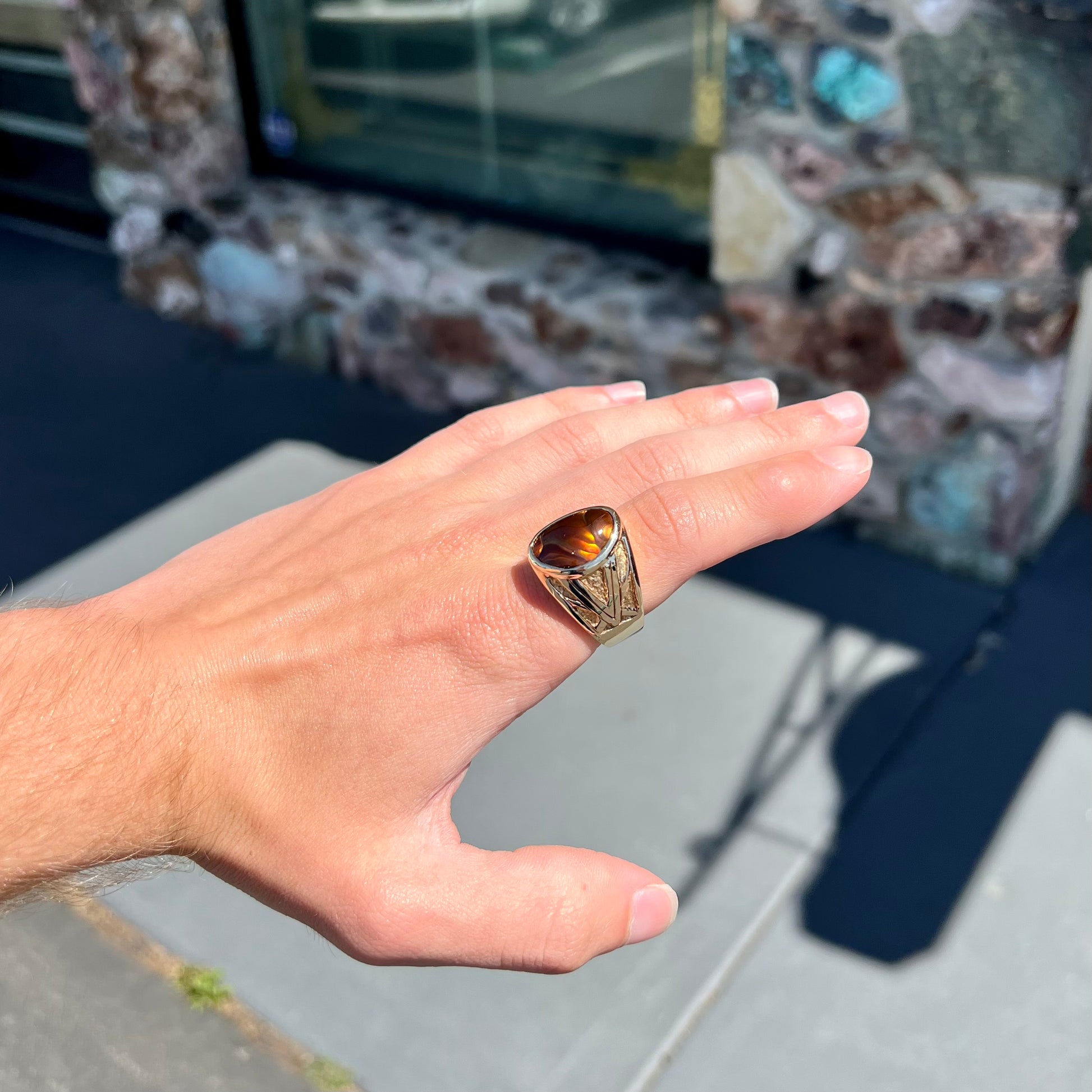 A solid, yellow gold men's fire agate ring.  The predominant color is red with green undertones.