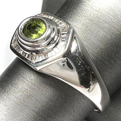 A sterling silver men's ring set with green peridot surrounded by baguette cut diamonds.