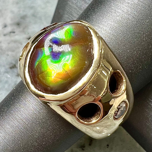 Men's rainbow fire agate ring set in yellow gold with champagne diamonds.  The ring style has holes.
