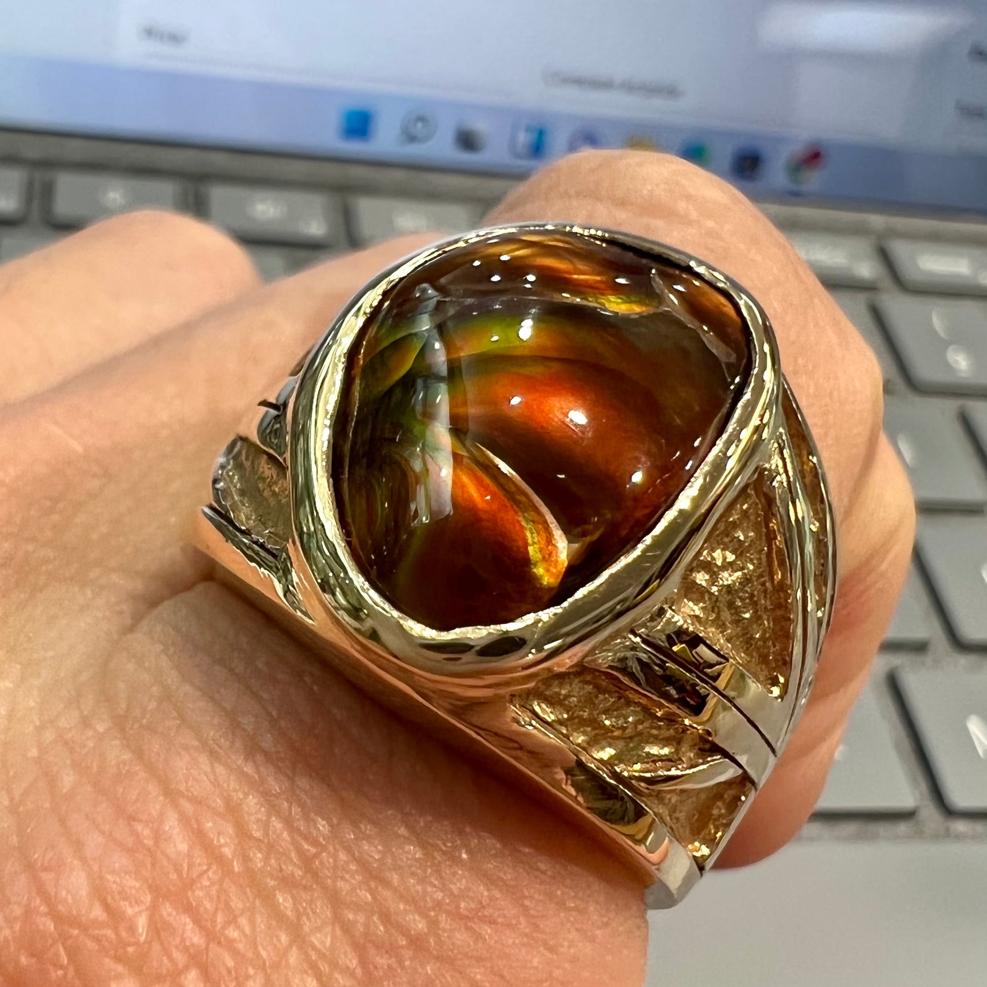 A solid, yellow gold men's fire agate ring.  The predominant color is red with green undertones.