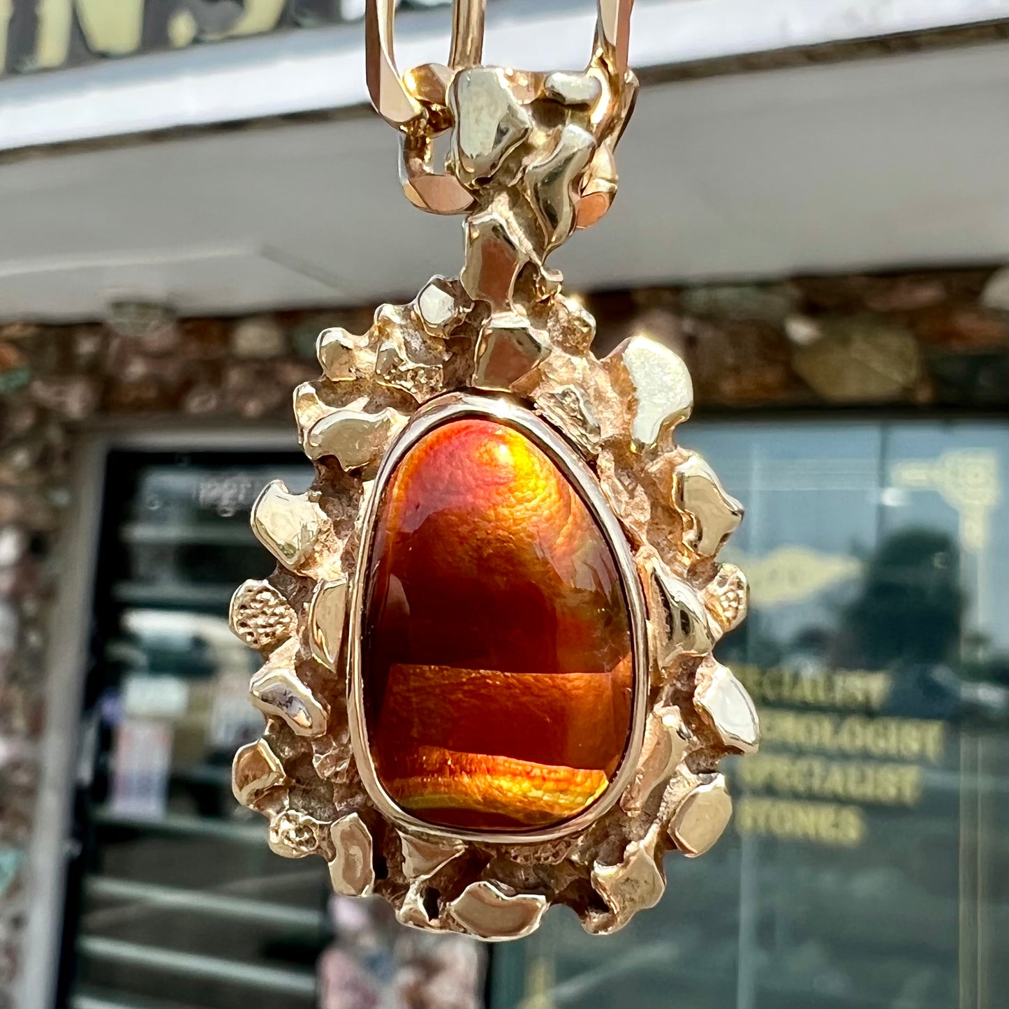 A gold nugget style pendant set with a freeform cabochon cut fire agate stone.