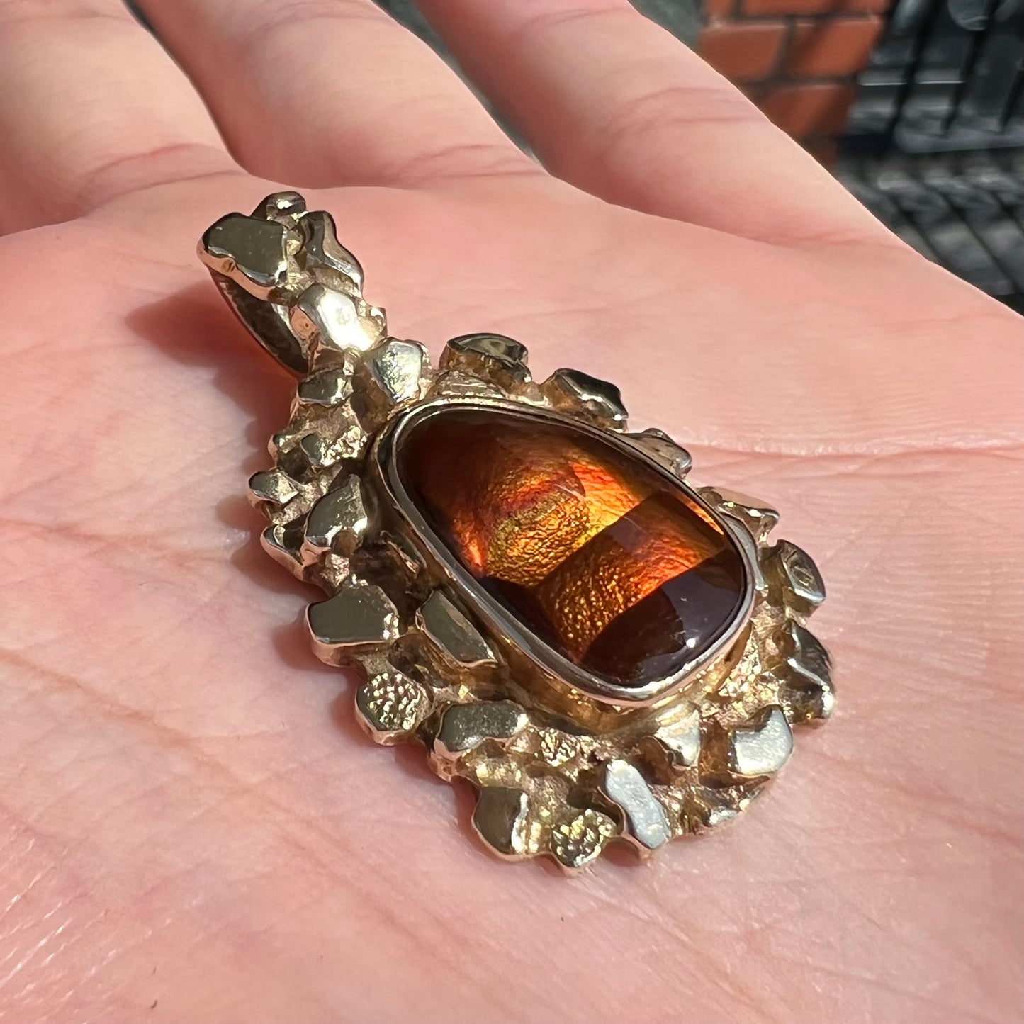 A gold nugget style pendant set with a freeform cabochon cut fire agate stone.