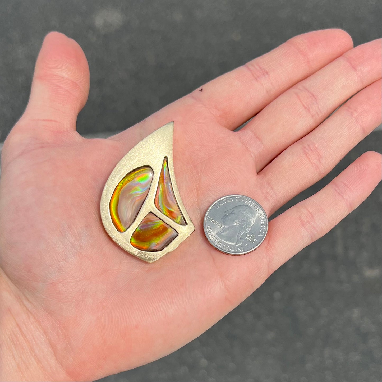 A men's gold pendant set with three fire agate stones.  The fire agate resembles an oil slick puddle.
