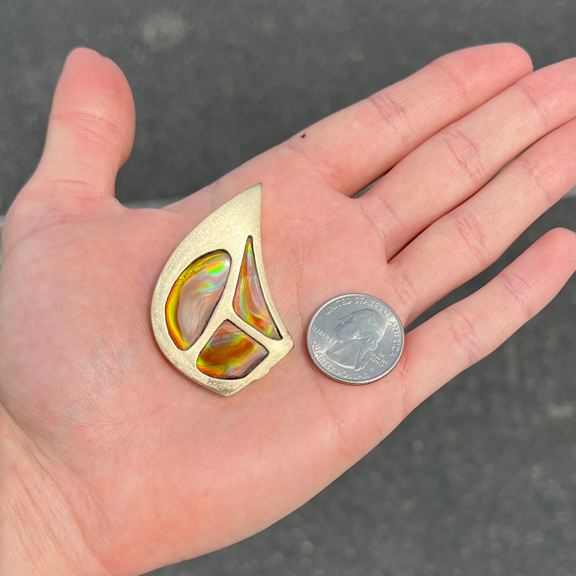 A men's gold pendant set with three fire agate stones.  The fire agate resembles an oil slick puddle.
