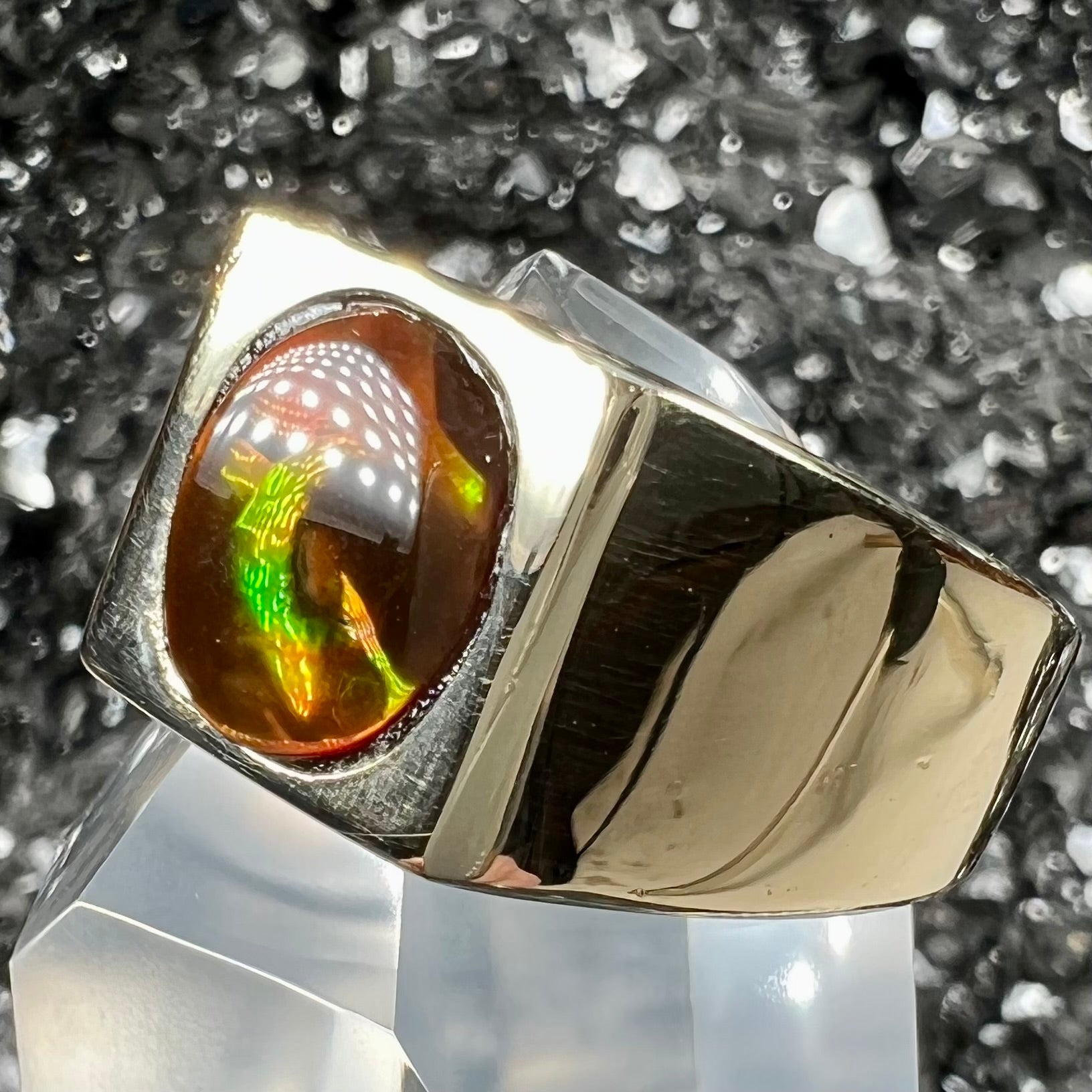 A men's yellow gold flush set fire agate solitaire ring.  The fire agate displays flashes of green, orange, and yellow.