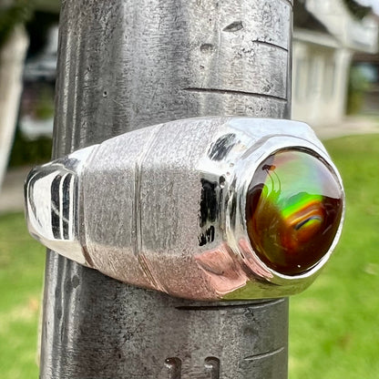 A round cabochon cut red and green fire agate set in a brushed metal white gold men's ring.