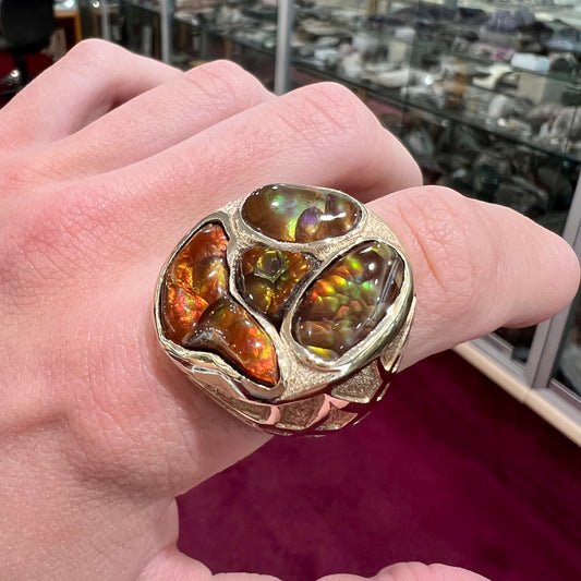 A yellow gold men's thug ring set with four fire agate stones resembling a spooky face.
