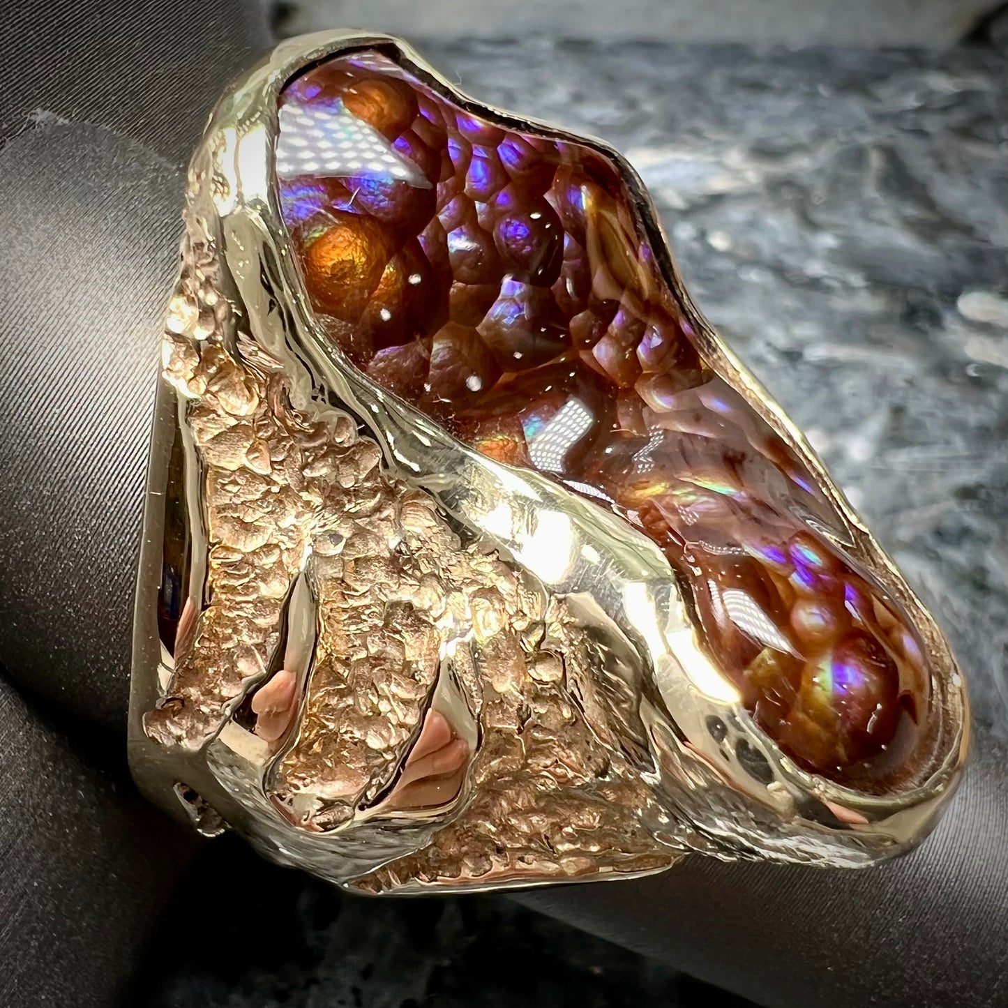 A men's Deer Creek fire agate solitaire ring cast in yellow gold.  The stone is predominantly purple.