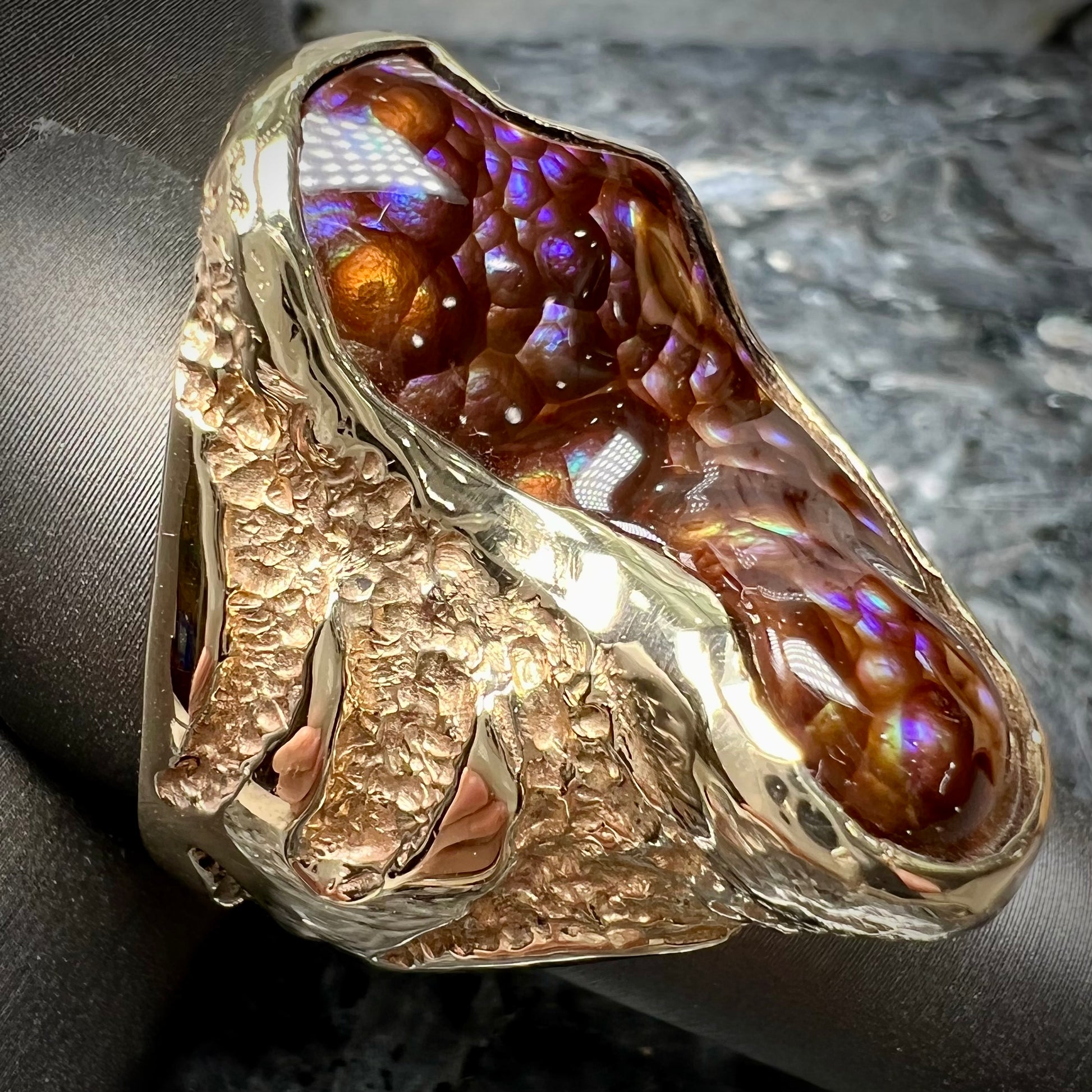 A men's Deer Creek fire agate solitaire ring cast in yellow gold.  The stone is predominantly purple.