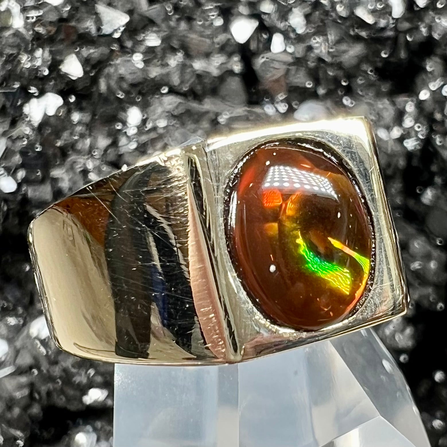 A men's yellow gold flush set fire agate solitaire ring.  The fire agate displays flashes of green, orange, and yellow.