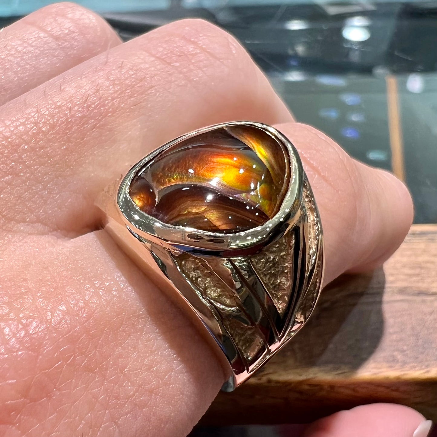 A solid, yellow gold men's fire agate ring.  The predominant color is red with green undertones.
