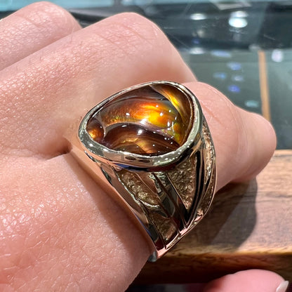 A solid, yellow gold men's fire agate ring.  The predominant color is red with green undertones.