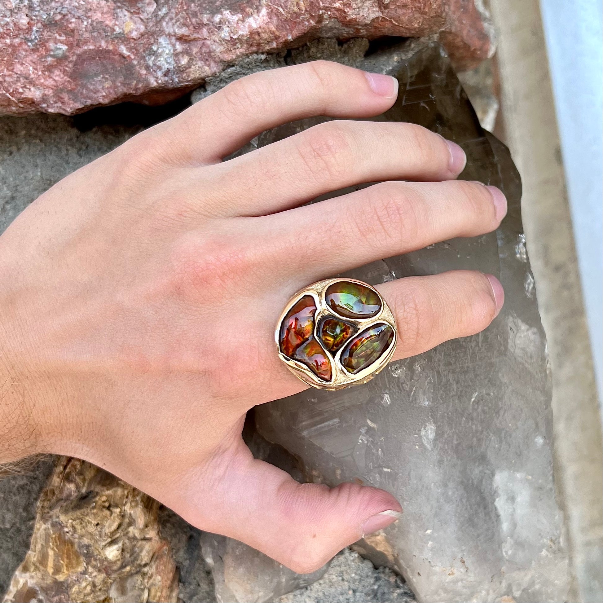 A yellow gold men's thug ring set with four fire agate stones resembling a spooky face.