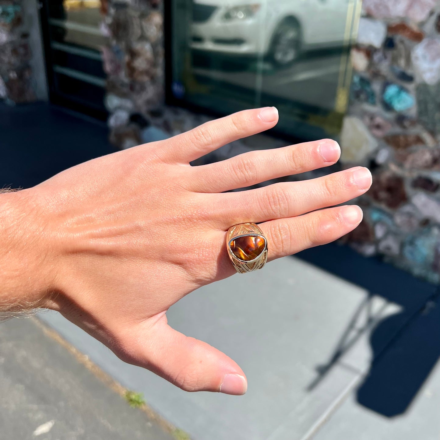 A solid, yellow gold men's fire agate ring.  The predominant color is red with green undertones.