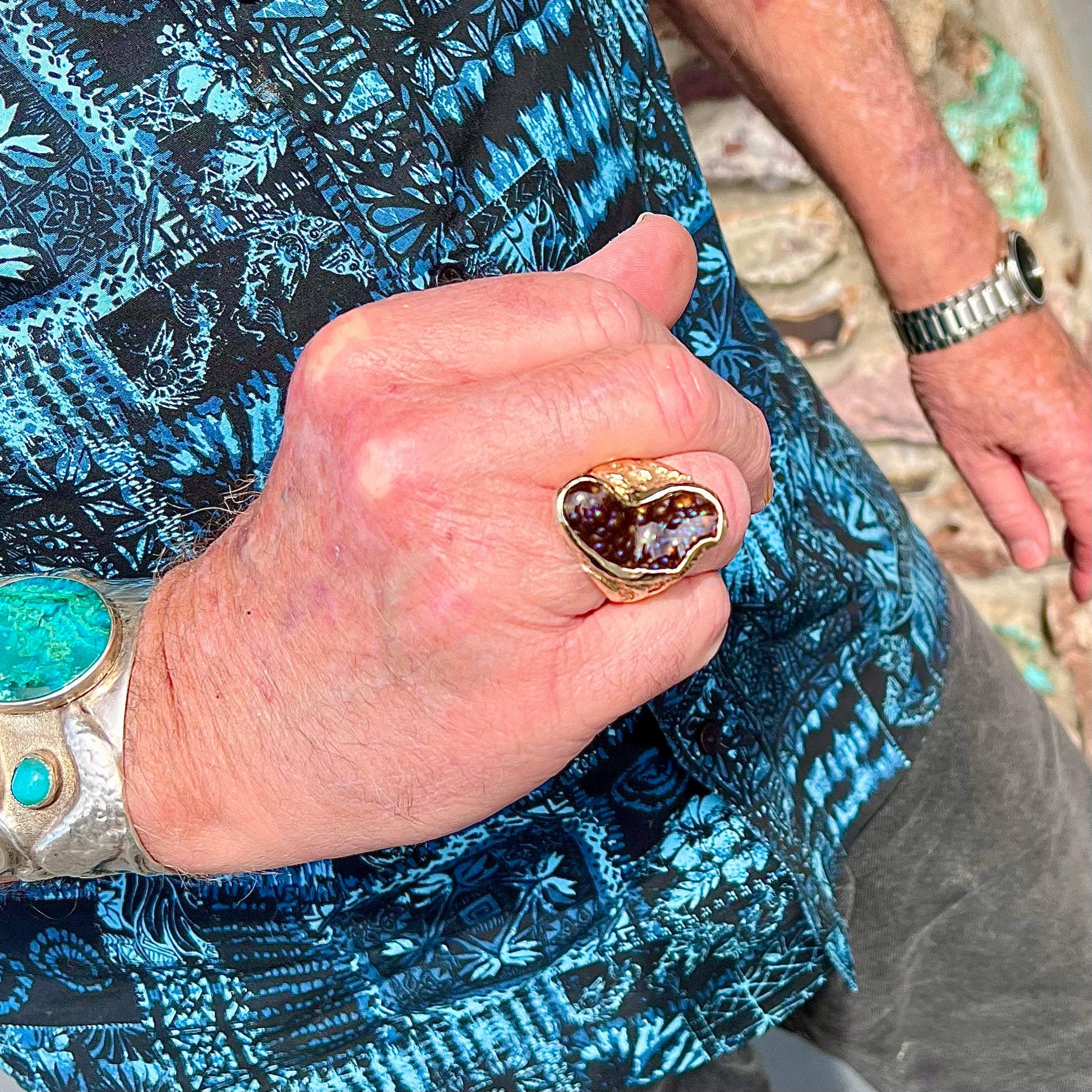 A men's Deer Creek fire agate solitaire ring cast in yellow gold.  The stone is predominantly purple.