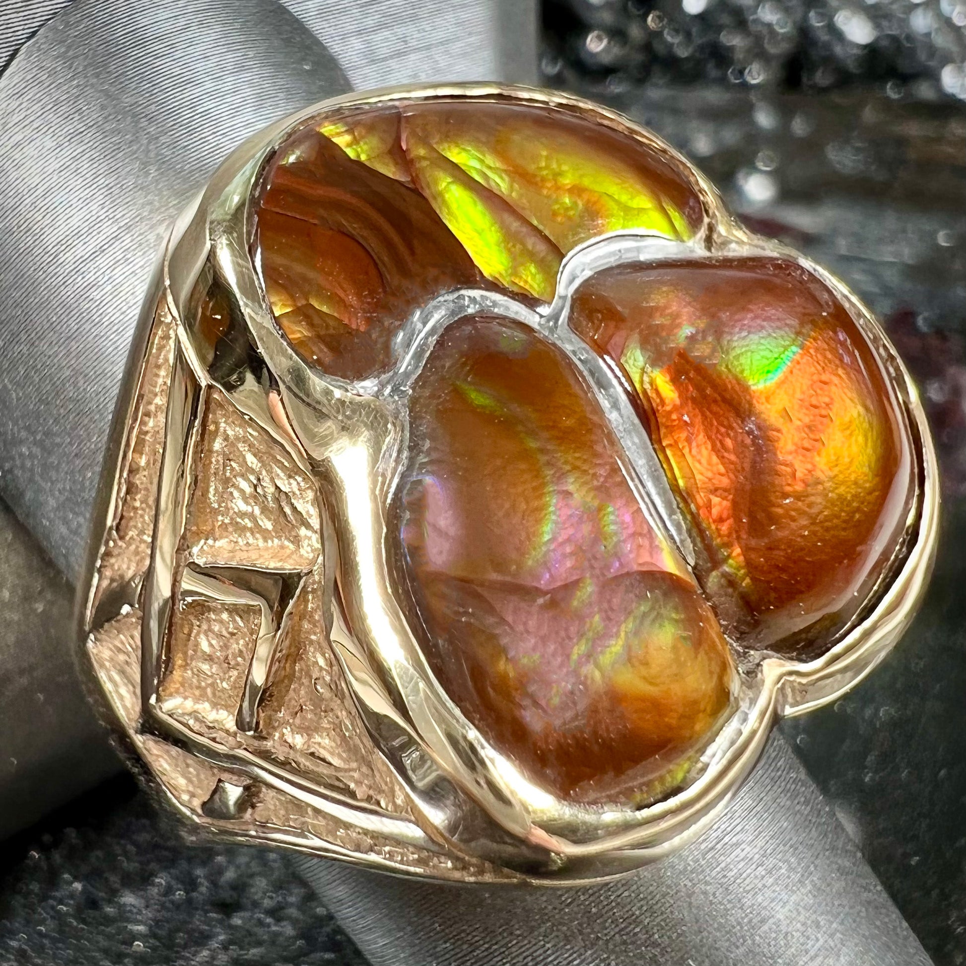 A men's yellow gold ring inlaid with three freeform cut fire agate stones.
