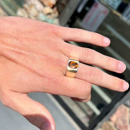 A men's yellow gold flush set fire agate solitaire ring.  The fire agate displays flashes of green, orange, and yellow.