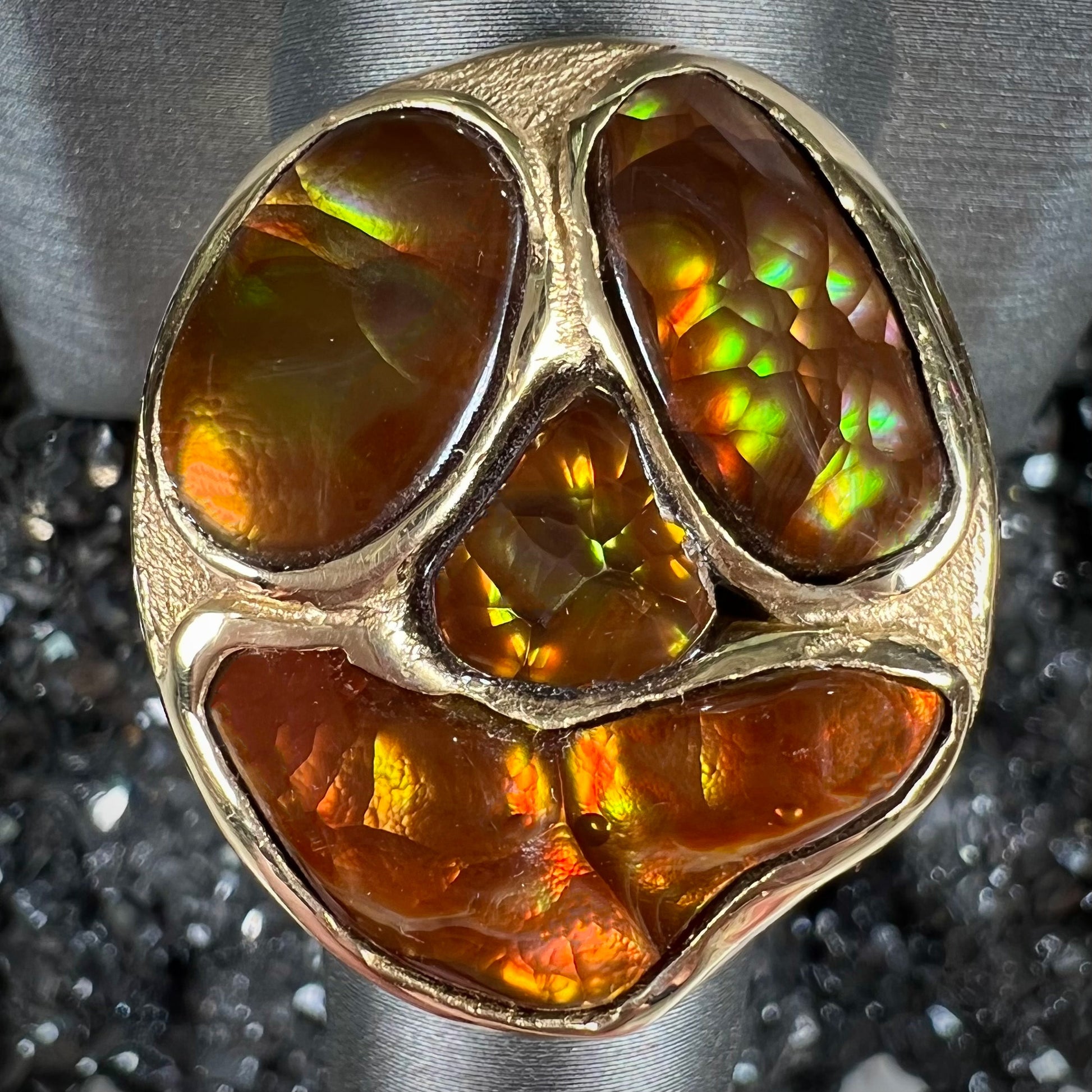A yellow gold men's thug ring set with four fire agate stones resembling a spooky face.