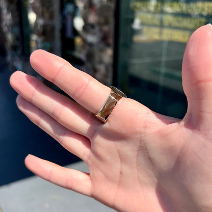 A solid, yellow gold men's fire agate ring.  The predominant color is red with green undertones.