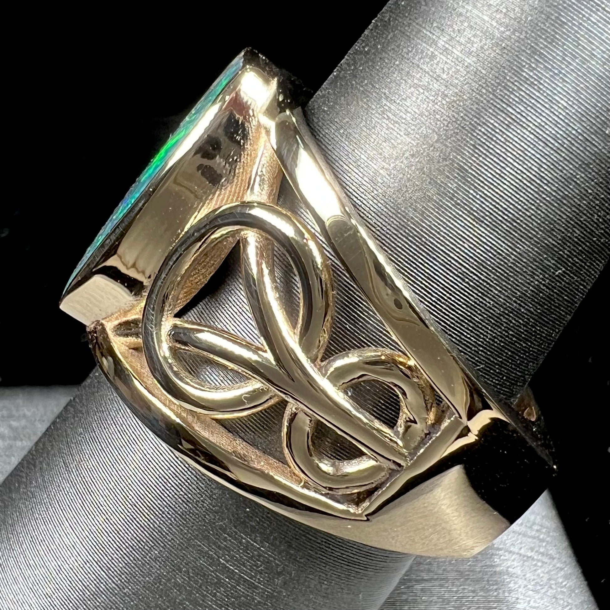 A men's natural Lightning Ridge, Australian black opal solitaire ring cast in yellow gold.