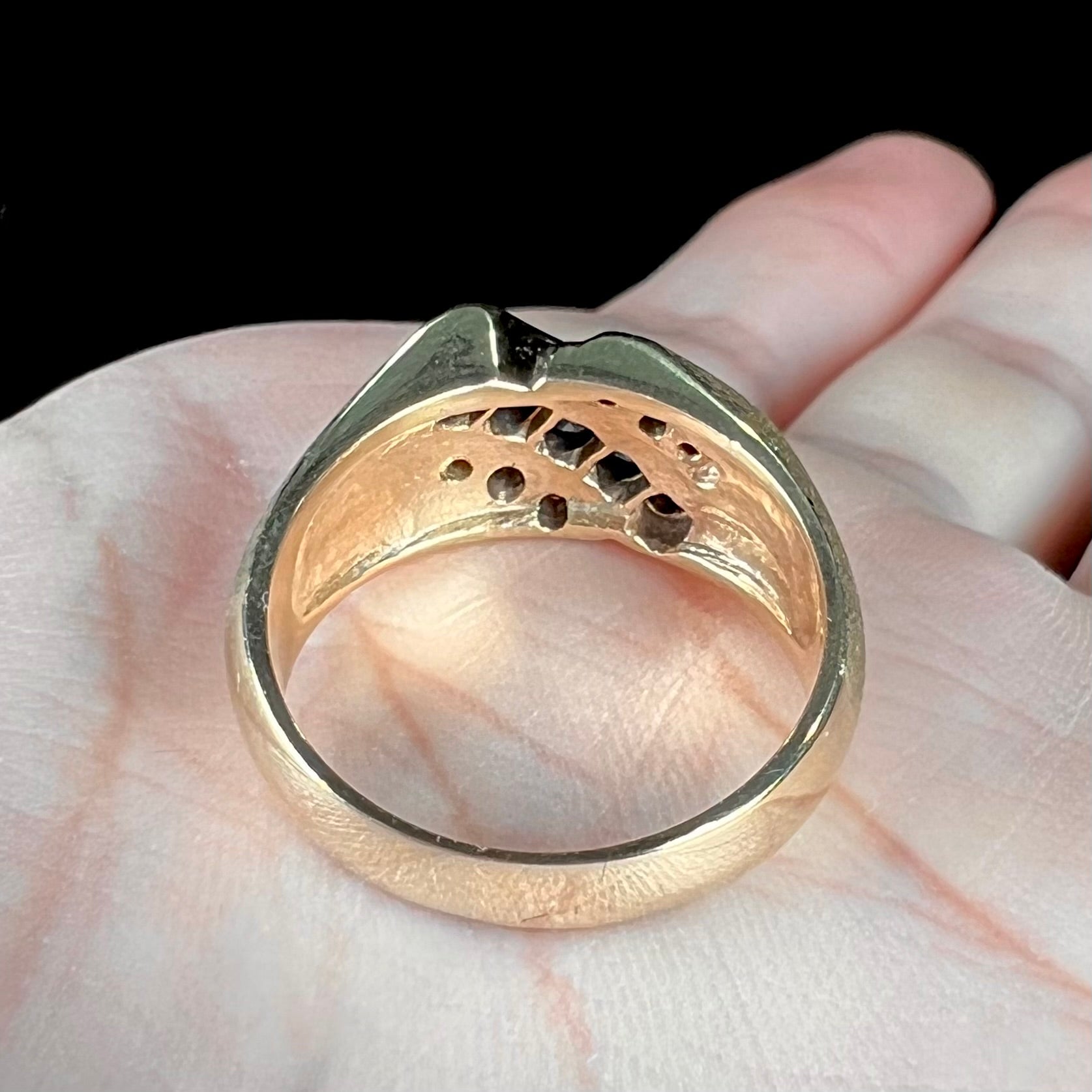 A men's yellow gold ring channel set with princess cut blue sapphires and diamonds.